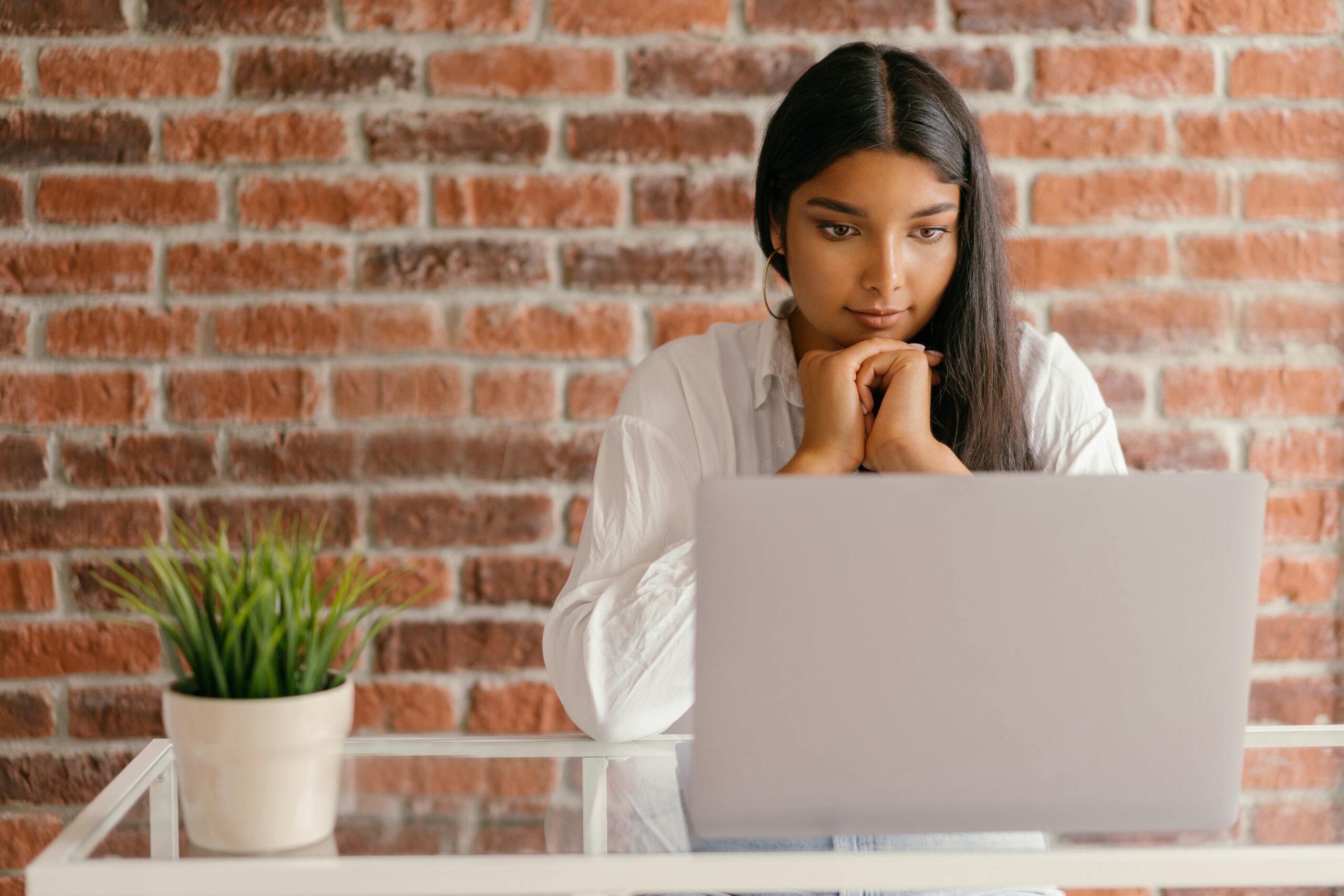 A young woman searching an entry-level marketing job on her laptop.
