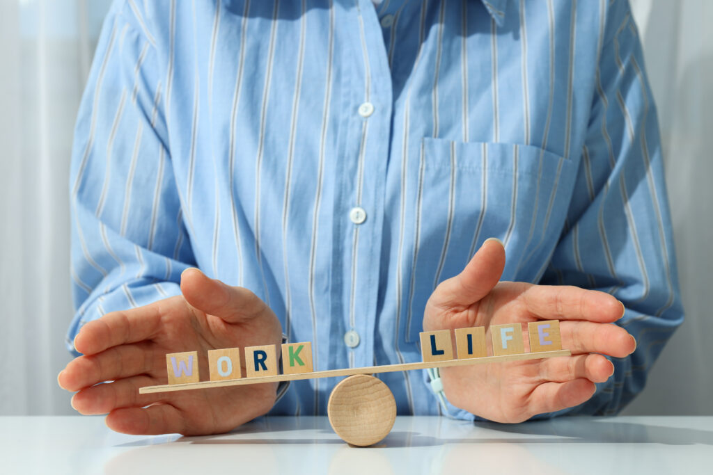 Hands balancing “work” and “life” blocks, symbolizing realistic work-life balance tips for a healthier lifestyle.