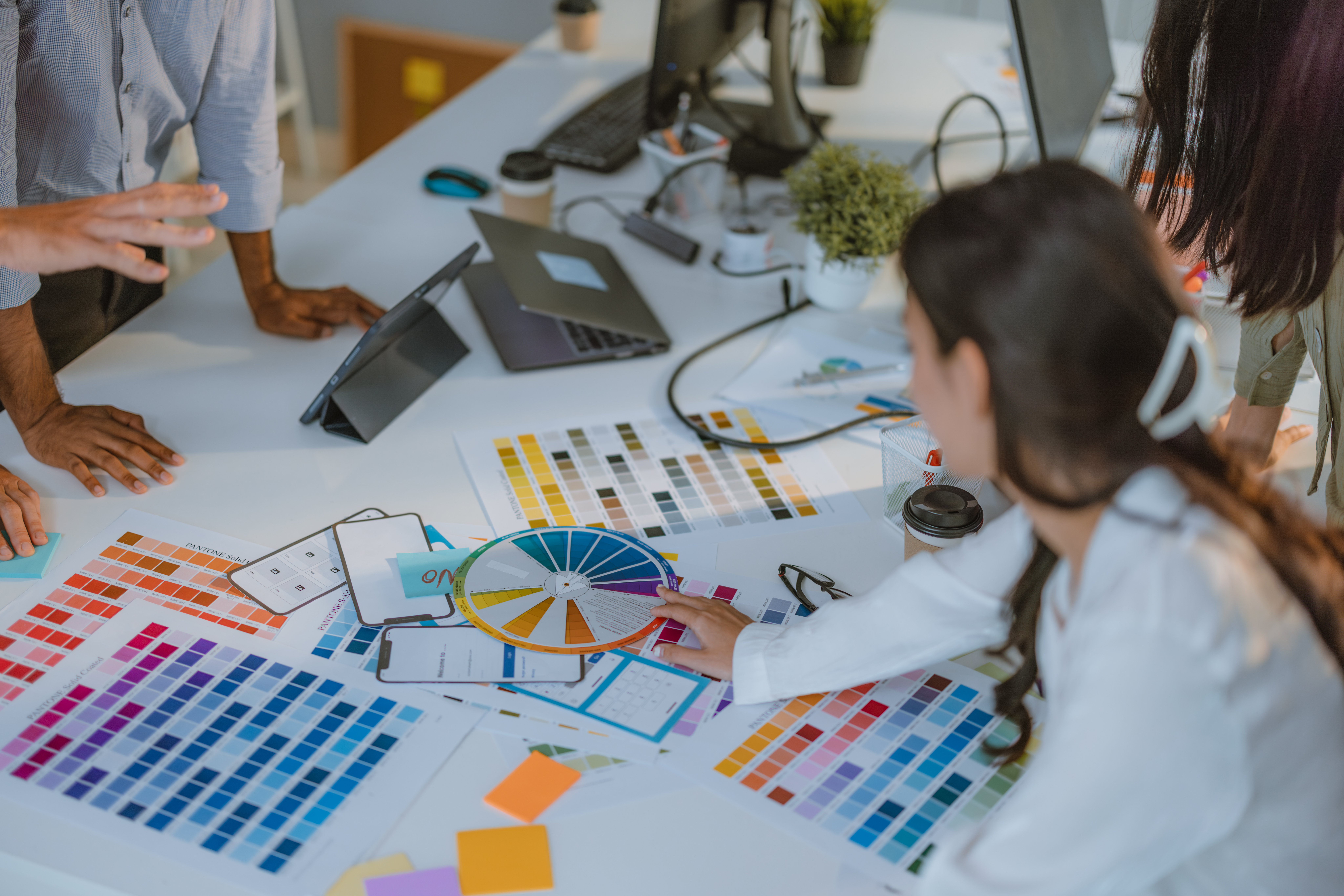 Professionals analyzing design elements and color schemes to strengthen brand development efforts.